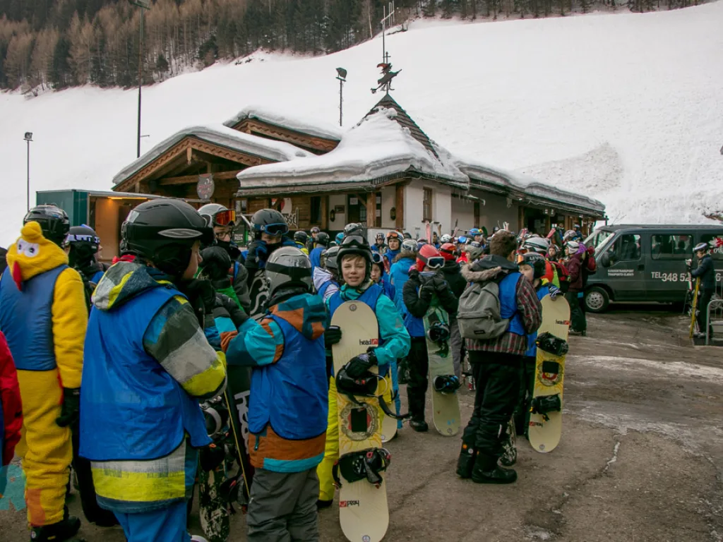 Gruppe versammelt sich mit Snowboards vor einem Gebäude.